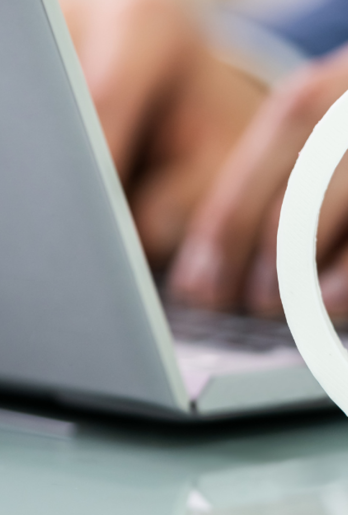 Billedet viser nogle hænder der taster på et laptop keyboard  i baggrunden, mens der er et hvidt coyright logo foran